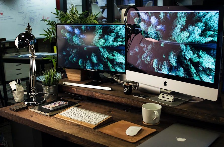 Two screens with birdโs eye shots of evergreen forests as background